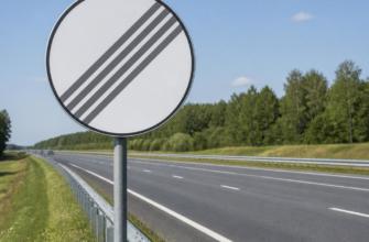 Дорожный знак конца зоны ограничения скорости на обочине трассы